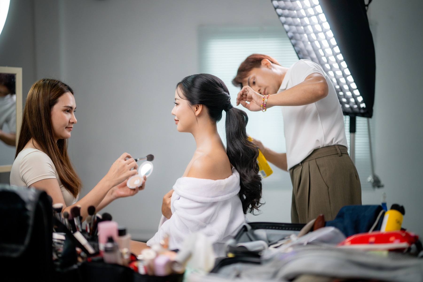 Hair and beauty professionals preparing a client in a bright studio